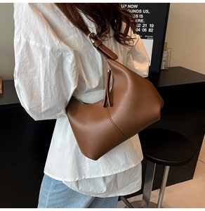 Close-up of brown faux leather hobo bag featuring vertical stitching and adjustable strap