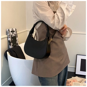 Dettaglio di una borsa a mezzaluna nera con finiture dorate e pelle liscia elegante