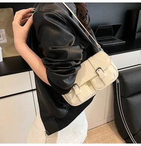 Detail of cream white leather shoulder bag featuring vintage pockets and black buckles