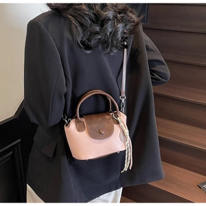 Pink and brown crossbody bag shown with bohemian tassel detail on indoor stairs