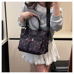 Détail d'un sac cabas imprimé cerise avec plusieurs poches zippées et bandoulière large