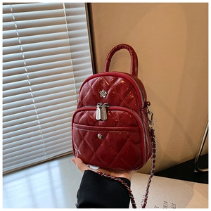 Close-up of red quilted leather mini backpack with silver metal flower and chain strap