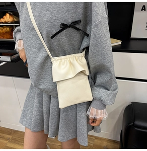 Détail du petit sac seau blanc crème en cuir litchi avec bords volantés sur modèle