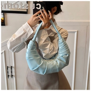 Close-up of a light blue pleated crescent handbag with a glossy finish and zipper closure