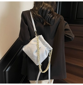 Quilted bucket bag with chain detail and drawstring closure shown on shoulder