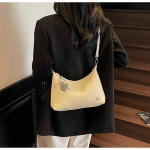 Detail of beige grainy leather hobo bag with silver heart charm and zip closure