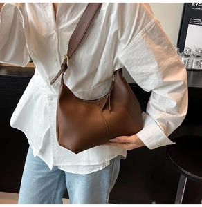 Detail of adjustable brown leather strap and golden buckle on a large hobo bag