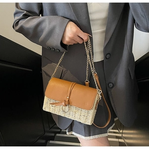 Detail of woven straw handbag with brown leather flap and stylish metal chain strap