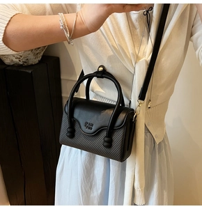 Détail du sac bandoulière noir avec texture matelassée et rabat en cuir lisse