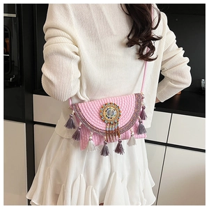 Detail of pink knitted crossbody bag with colorful ethnic beadwork and fringe tassels