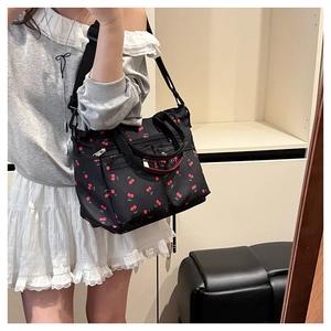Détail du sac fourre-tout en nylon noir avec imprimés cerises et large bandoulière réglable