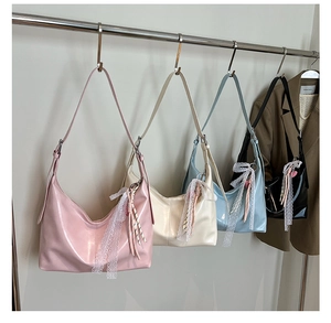 Close-up of four colored glossy hobo bags with lace charms on a display rack