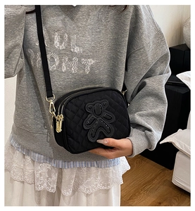 Close-up of black quilted crossbody bag featuring a cute sequin bear patch and gold zippers