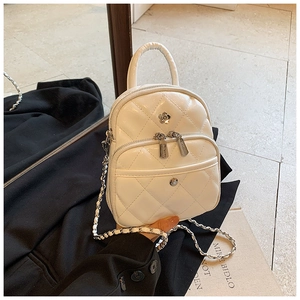 Detail of white quilted crossbody bag with floral metal buckle on a black blazer