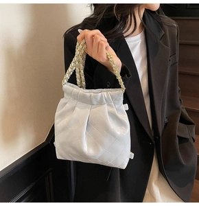 Détail d'un sac à bandoulière matelassé bleu clair avec chaîne dorée et plissages