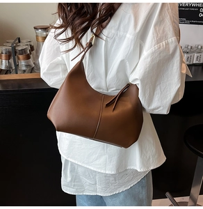 Brown leather crescent hobo bag shown being worn by a model in a casual setting