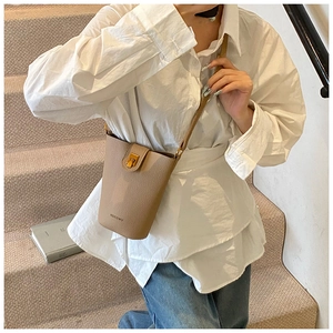 Chic tan pebble leather bucket bag styled on a staircase for a modern casual aesthetic