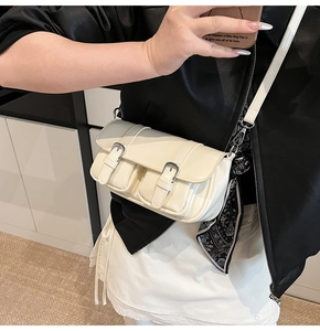 Detail of cream PU crossbody bag featuring buckled pockets and a decorative patterned scarf