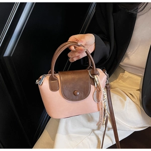 Close-up of pink crossbody bag with tennis racket charm and contrast brown handle