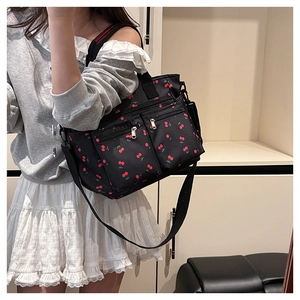 Détail du sac cabas noir avec imprimé cerises, fermetures éclair en métal et bandoulière