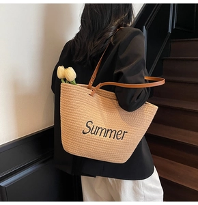 Détail d'un sac cabas en paille tissée avec broderie Summer noire et anses en cuir brun