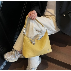 Detail of yellow lychee leather hobo bag with silver zipper and grape charm decoration