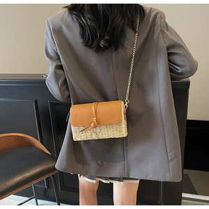 Detail of hand-woven straw crossbody bag with brown leather flap and gold chain strap