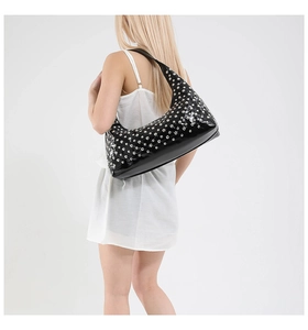 Detail of black patent leather underarm bag with dense silver metal rivet decorations