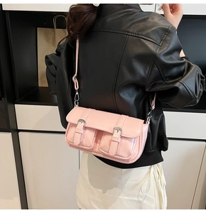Detail of pink faux leather crossbody bag with dual metal buckles on a black jacket