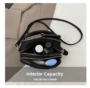 Detail showing high-capacity interior of black nylon crossbody bag with 3 zipper pockets