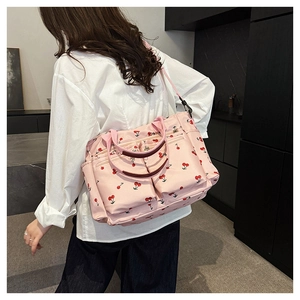 Vue détaillée du sac cabas rose à imprimé cerise avec bandoulière sur un mannequin