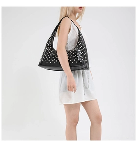 Close-up of black PU leather hobo bag with silver studs and crescent shape on a model