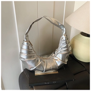 Detailed view of silver metallic pleated crescent bag with high-shine texture and zip closure