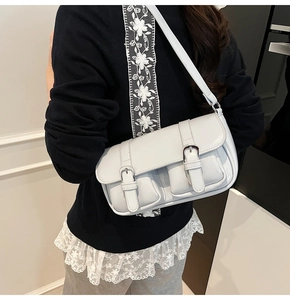 Detail of light blue vintage shoulder bag with dual pockets and silver buckles on model