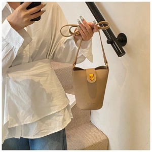 Detail of light khaki leather bucket bag with gold hardware twist lock and logo