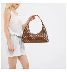 Detailed view of dark brown crescent bag featuring metallic silver rivet decorations