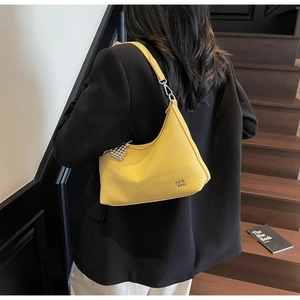 Detail of yellow lychee textured hobo bag with silver heart pendant on a model