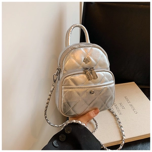 Detail of silver quilted mini bag with metallic mirror finish and chain shoulder strap