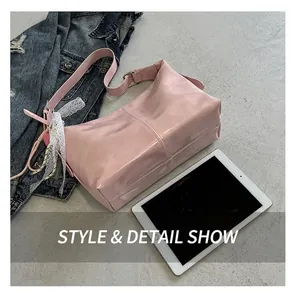 Pink glossy faux leather shoulder bag with decorative lace pendant and stitched seam