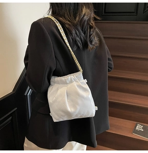 Detailed view of white quilted drawstring bucket bag with gold-tone chain strap