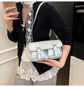 Detail of light blue glossy leather handbag showing front pockets and silver buckles