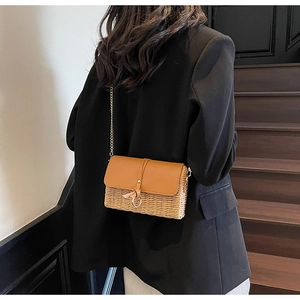 Detail of retro straw shoulder bag with brown leather flap and gold chain strap