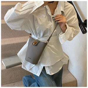 Close-up of gray pebble leather bucket bag with gold twist-lock and fine strap detail