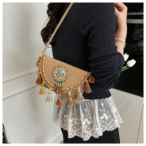 Detail of ethnic straw crossbody bag featuring colorful tassels and beaded circular medal
