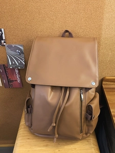 Vintage brown PU leather travel backpack for commuting and students on a wooden stool