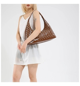 Detail of a brown glossy leather hobo bag with silver studs and polished finish