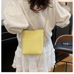 Detail of yellow lychee pattern leather bucket bag with metal and leather chain strap