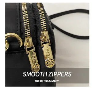 Detail shot of smooth gold-tone dual zippers on a premium black crossbody phone bag