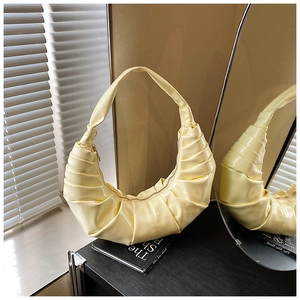 Close-up of pleated crescent bag in cream faux leather with metallic zipper and texture