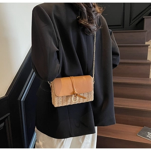 Straw woven crossbody bag with brown leather flap and chain strap on female model